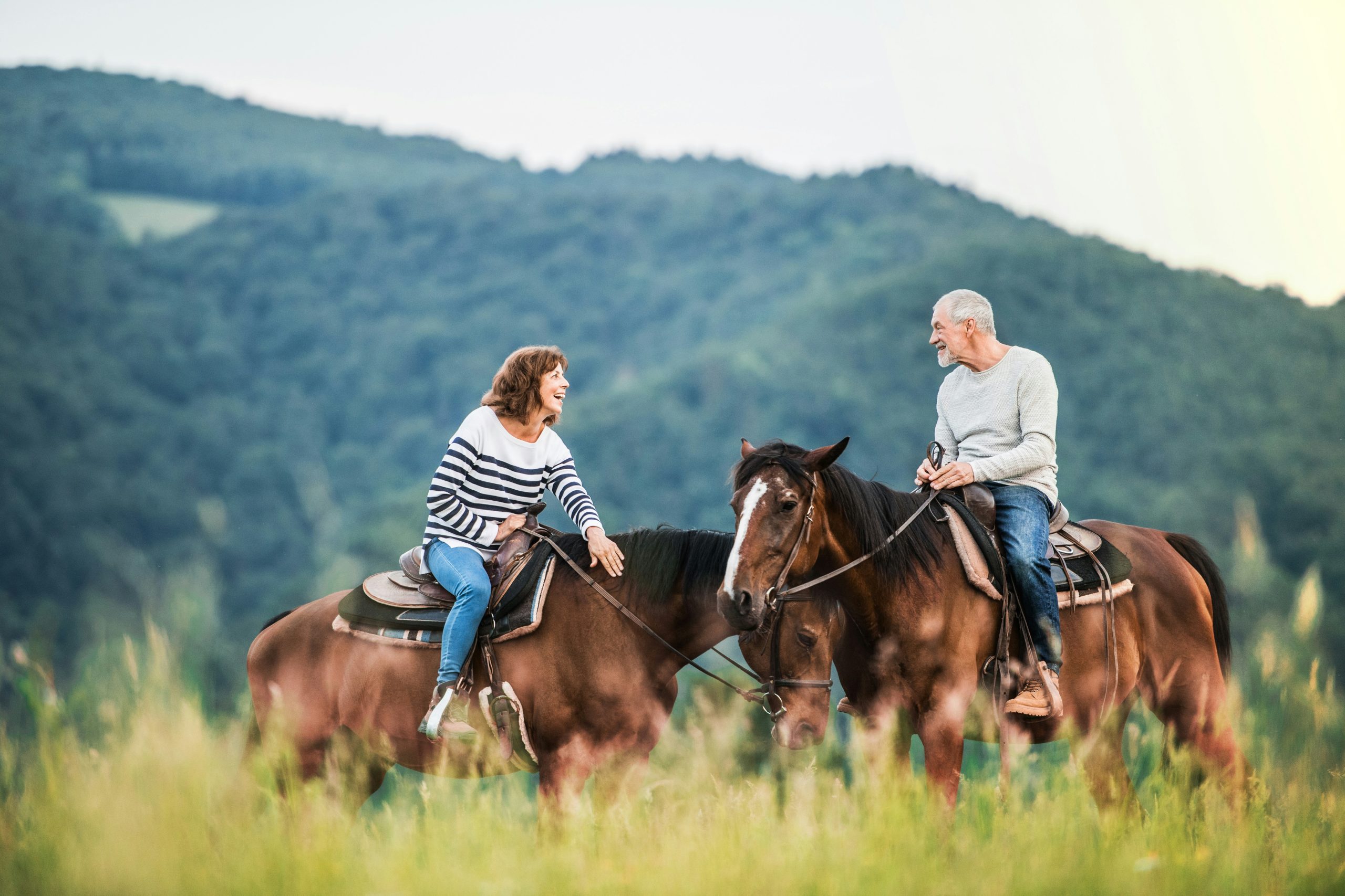 A couple riding horses across an open meadow