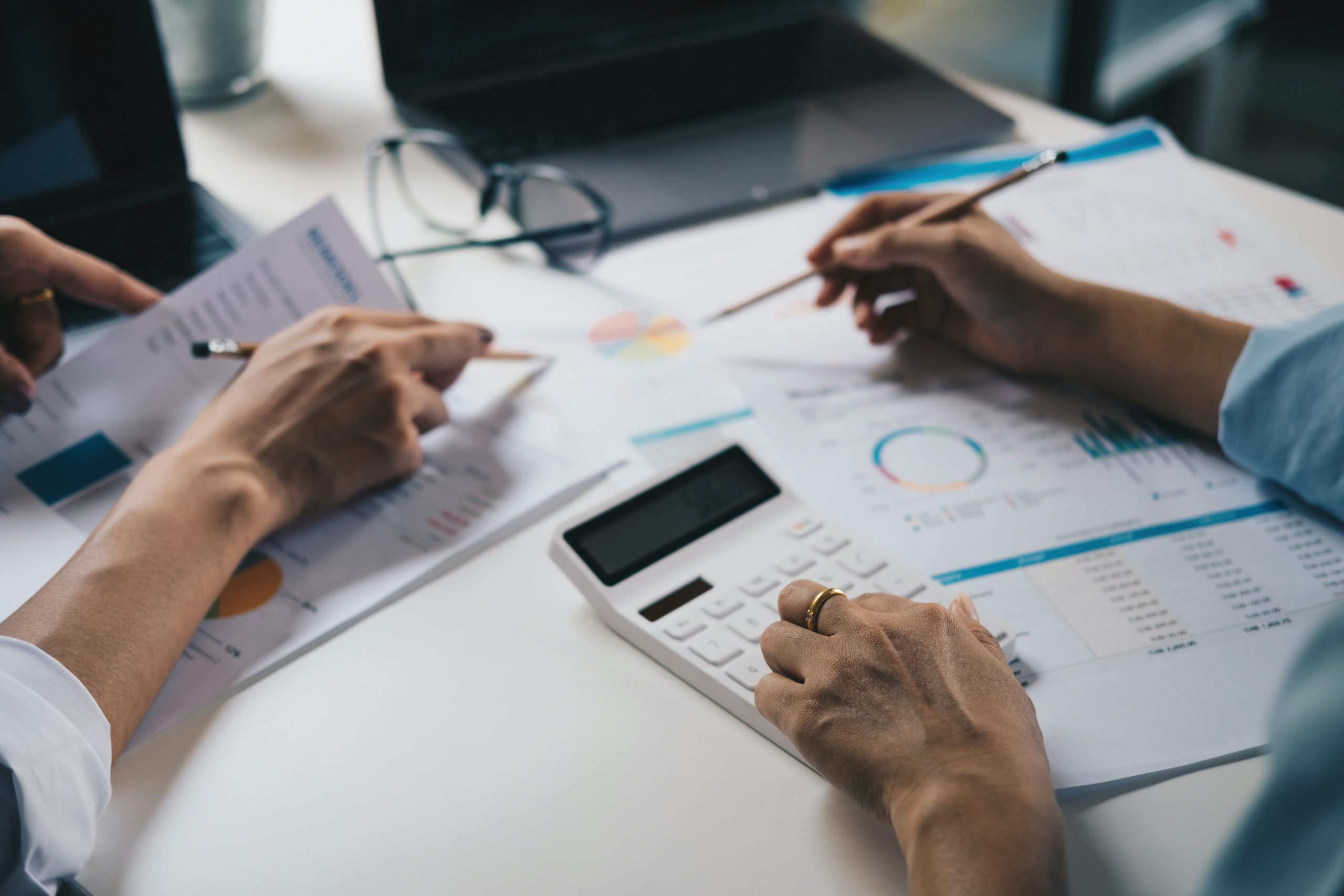 Close-up hands of an advisor and client at a desk with a calculator and documents