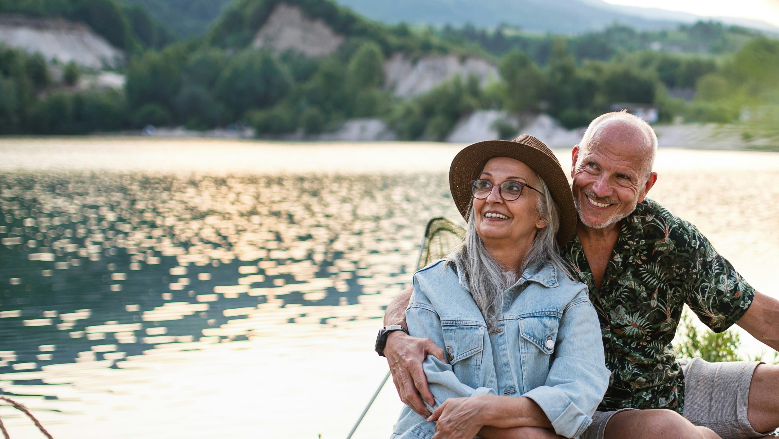 An older couple in outdoor jackets hiking together through autumn woods