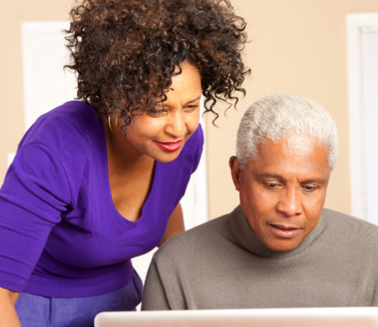 A female advisor leaning in to assist a senior male client