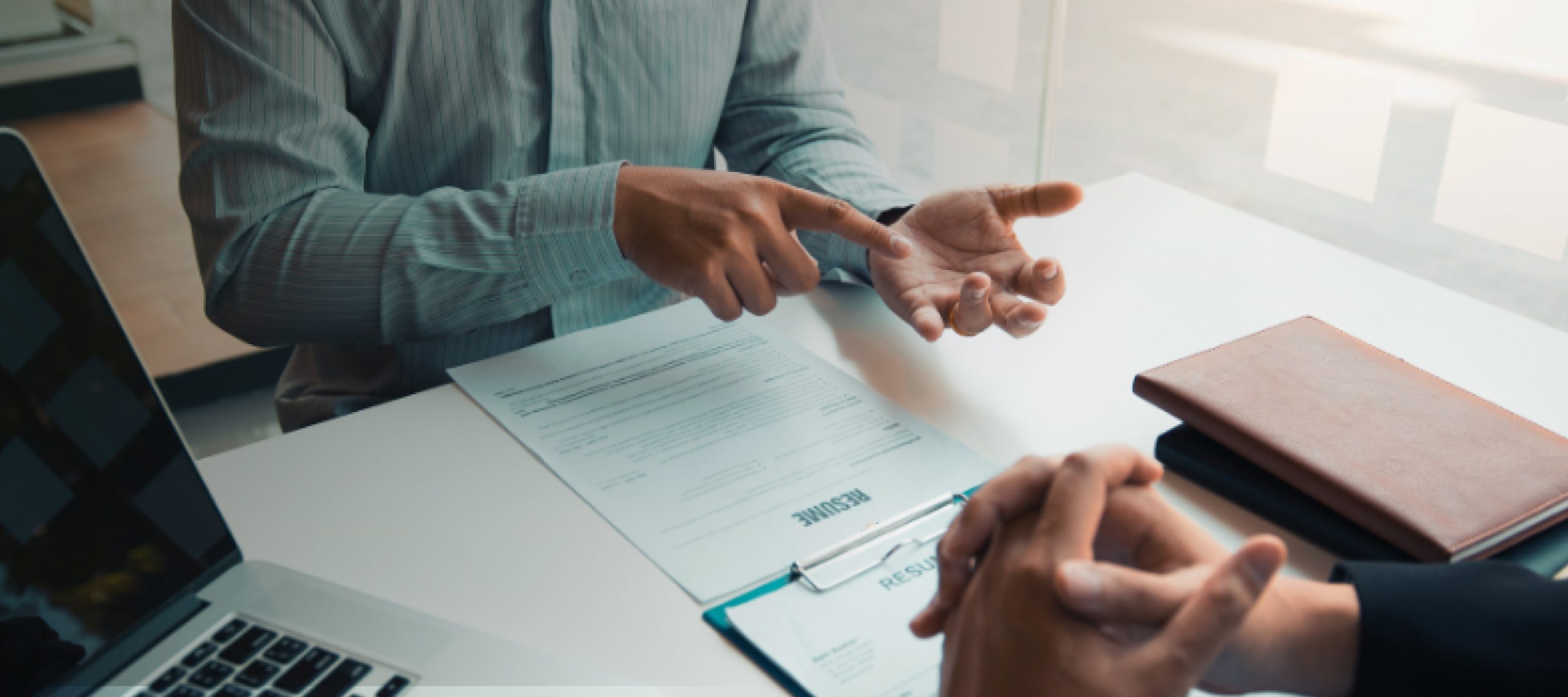 Hands reviewing and pointing at documents on a desk during a meeting